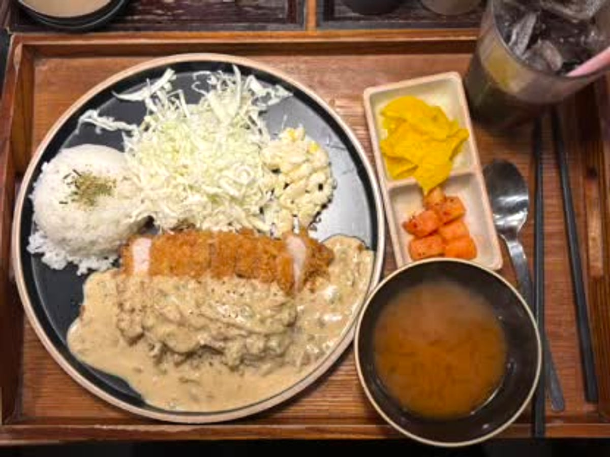 A Korean katsu tray with pork cutlet, rice, cabbage, soup, and side dishes in Hongdae